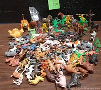 Wide-angle image showing many assorted plastic animals and figures including horses, cowboy and indian figures, dogs, and other creatures laid out on a table.