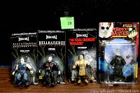 Four sealed horror action figures displayed side by side on black surface with black background. Figures are individually packaged in blister card format.