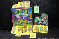 Full view of the TMNT collector's case, Michelangelo figure in packaging, and 20 trading cards/stickers displayed in front.