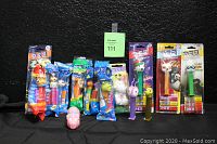 Full lot image showing all 15 PEZ dispensers, 12 sealed in various colorful packaging and 3 loose with visible characters and colors