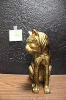 Front view of the vintage gold-colored metal tiger figurine, showing detailed facial features and seated posture.