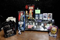 Front view of the Star Wars collectibles lot showing PEZ dispensers set, action figures, and Mighty Muggs figure in original packaging on a wooden surface against a black background.