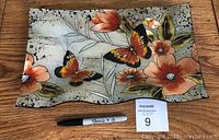 Full view of decorative rectangular glass tray displaying butterflies, flowers, and leaves painted in orange, black, green, and silver glitter accents.