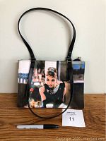 Full view of the rectangular Audrey Hepburn purse with black handles, showing the image and purse design.