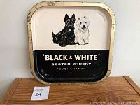 Front view of the vintage metal serving tray showing Buchanan's Black & White Scotch Whisky label and the Scottie and Westie dog images with visible wear spots on the metal.