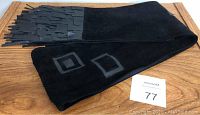 Black suede scarf displayed on wooden surface showing leather geometric square accents and fringes