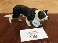 Side view of Border Collie figurine showing textured black and white fur with tag attached.