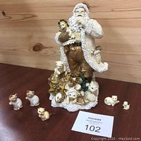 Santa Claus figurine holding a cat with five vintage cat collectibles arranged around it on a wooden surface