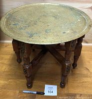Photo shows the full table with removable large brass top on wooden folding legs with a marker for scale.