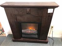 Front view of dark brown wooden mantel surround with electric flame insert