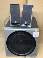 Two rectangular Logitech satellite speakers resting on top of a black Logitech subwoofer with front mesh bass port.