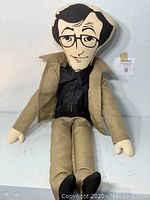 Full frontal close-up of the Woody Allen doll seated, showing outfit and face details.