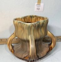 Front angled view of the square vase showing its thick handles and glazed surface with earth-tone color variations.