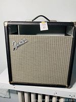 Front view of Fender amplifier cabinet showing the original Fender logo on the grill cloth and black tolex covering with metal corner guards and top handle.