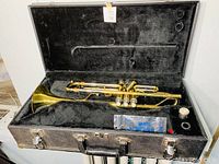 Jupiter trumpet resting in an open black hard shell case lined with velour fabric. Includes mouth guard and mouthpiece brush visible in the case.
