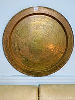 Full front view of large circular bronze plate hanging on wall, showing overall size and shape.