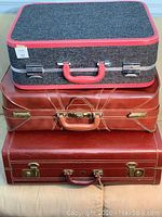 Front view of three suitcases stacked with fabric suitcase on top and two brown leather suitcases below