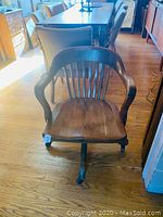 Front view of the oak bankers swivel chair with rounded arm back on casters.