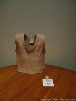 Front view of the blush pink shirt-shaped vase on wooden table