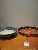 Photo shows the ceramic bowl and the astrological tray side by side on a wooden surface under neutral lighting.