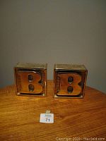 Front view of two brass bookends showing prominent embossed letter 'B'