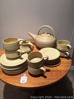 Overall view of tea service on wooden table including teapot, cups, plates, saucers