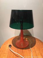 Full view of lamp showing orange plastic base, green translucent shade, and original cord