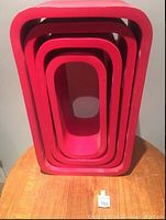 Nested set of four red floating shelves displayed on a table to show relative sizes and finish.