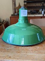 Green enamel metal light shown from the side on a wooden surface with ruler.