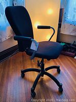 Side perspective of the black executive office desk chair showing the padded seat, backrest, and armrests with textured grips.