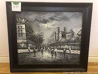 Angular full view of framed black and white Parisian street oil painting showing street with people and buildings.