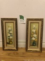 Two framed vertical oil paintings by G. Mauger, floral arrangements in vases, side by side against a wall.