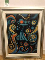 Full view of framed vibrant abstract multi media painting with swirling circular shapes in blue, orange, gold, and black.