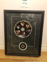 Framed NHL collectors plate with miniature jerseys representing Original Six NHL teams and a puck below, both behind glass in a black frame.