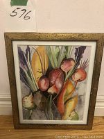 Full view of framed watercolor painting depicting colorful vegetables with gold-tone frame and white mat around artwork.