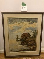 Framed original oil painting showing boathouse on lake with cloudy sky, signed P. Kits bottom left.