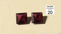 Two square garnet gemstones placed side by side on a light background showing color and shape.