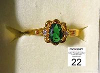 Front view of ring showing oval green center stone and surrounding diamond accents on band.