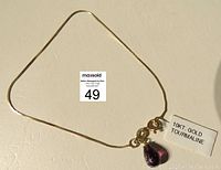 Full view of the fine 10K gold chain ankle bracelet with purple tourmaline pendant, tag stating '10KT GOLD TOURMALINE'.