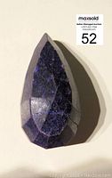 Faceted teardrop-shaped purple gemstone side