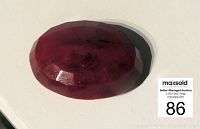 Close-up of red faceted oval ruby on white background showing color and cut