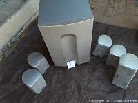 Full view of the subwoofer and five satellite speakers arranged on ground