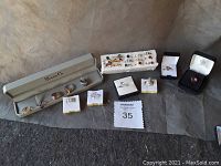 Photo of entire lot arranged on grey surface, showing rings in Shane Co case, on foam, and in individual holders.