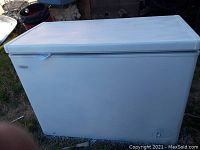 Full side view of the white chest freezer showing scuffs and marks on exterior surface.