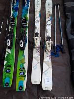 Two pairs of children's skis side by side showing bindings and size details.