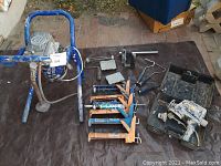 Wide view of painting tools and airless sprayer laid out on black tarp
