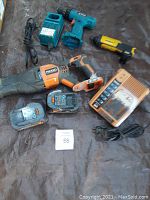 Overview of cordless tools including Ridgid sawzall with batteries and charger, Makita drill, Makita charger base, and Dewalt drill without charger.