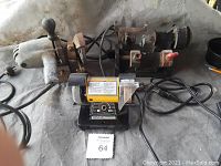 Three grinding and key cutting tools visible: vintage portable grinder, small yellow bench grinder, and metal key cutting machine with cords and controls.