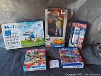 Lot contents including Star Wars action figure, solar robot kit, Pass the Pigs game, and two puzzles all sealed in original packaging.