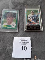 Photo showing both Troy Aikman rookie cards, one signed in hard plastic case with plaque, one unsigned in clear plastic holder.